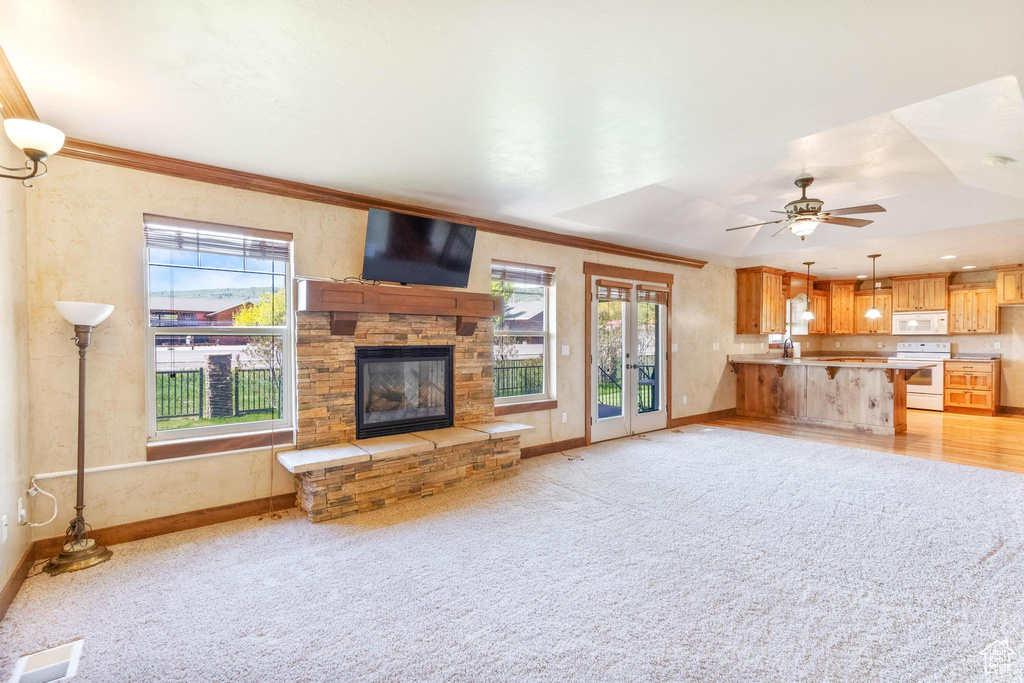 Unfurnished living room with healthy amount of natural light, ornamental molding, a stone fireplace, and baseboards