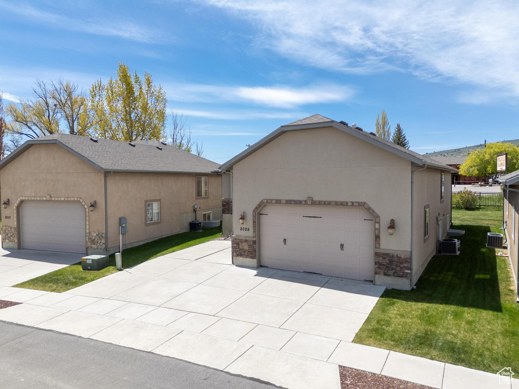 View of front of property with a garage, a front lawn, concrete driveway, stucco siding, and stone siding