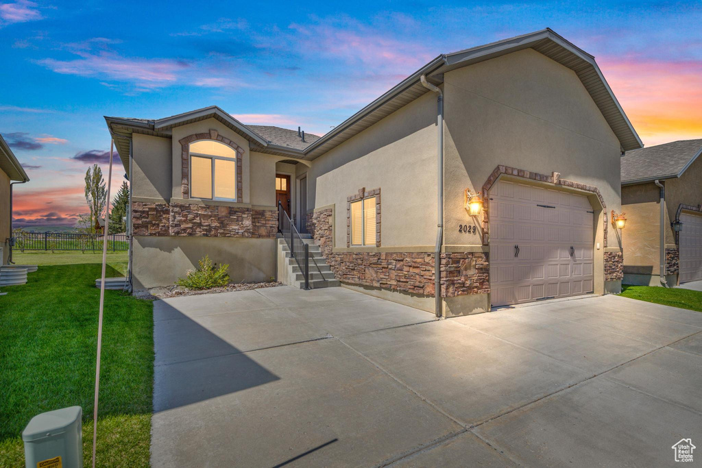 View of front of house with stone siding, driveway, stucco siding, and a garage