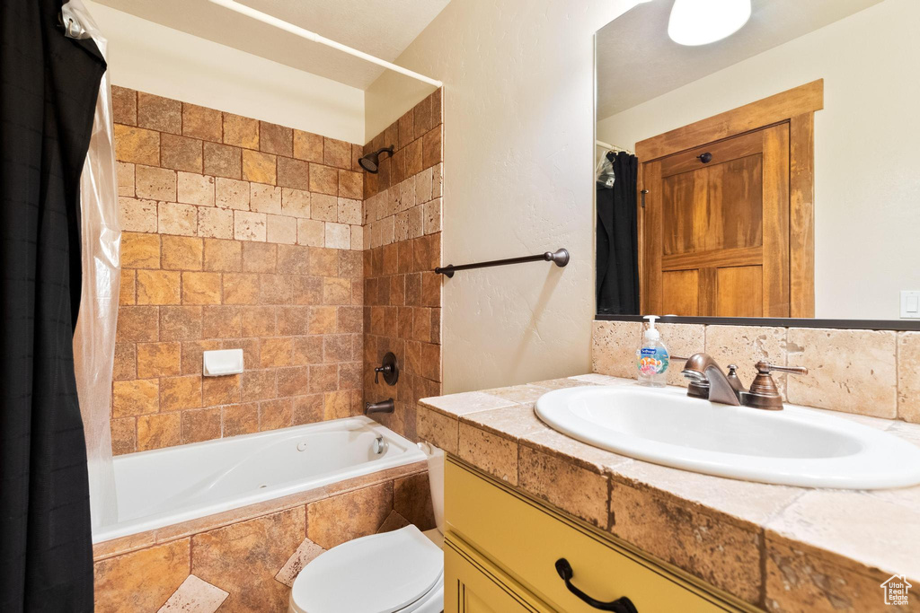 Full bath with vanity, tiled shower / bath, and toilet