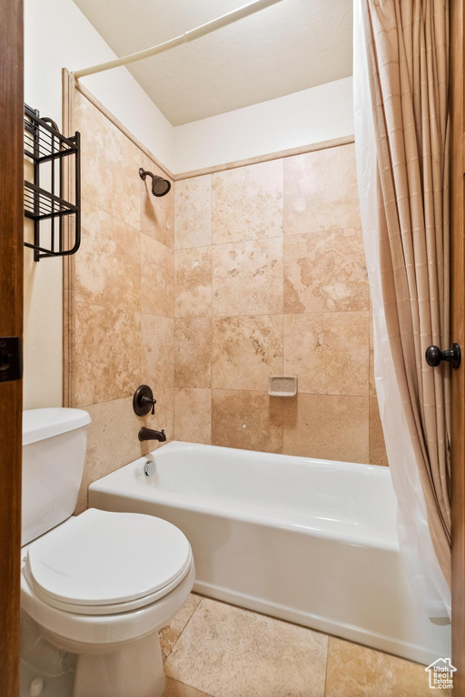 Full bathroom with shower / bath combo, toilet, and tile patterned flooring