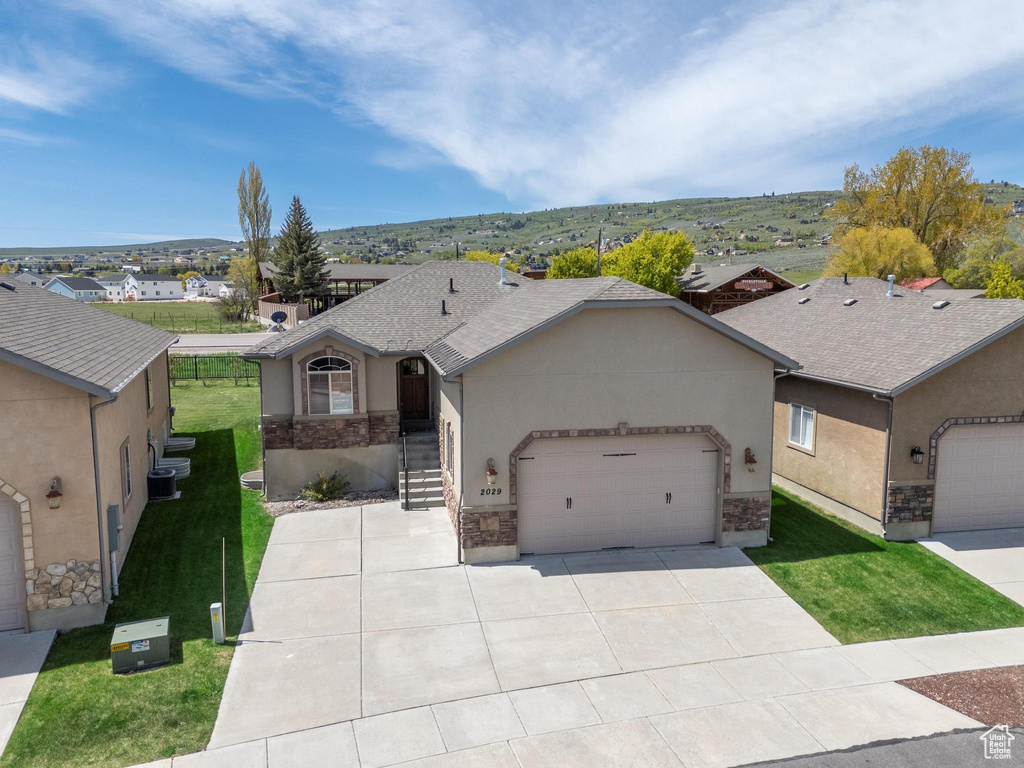 Single story home featuring stucco siding, a garage, stone siding, and a front lawn
