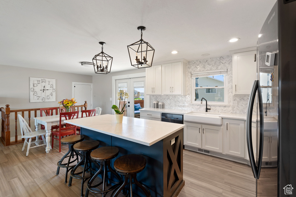 Kitchen featuring freestanding refrigerator, a sink, light countertops, a breakfast bar area, and recessed lighting