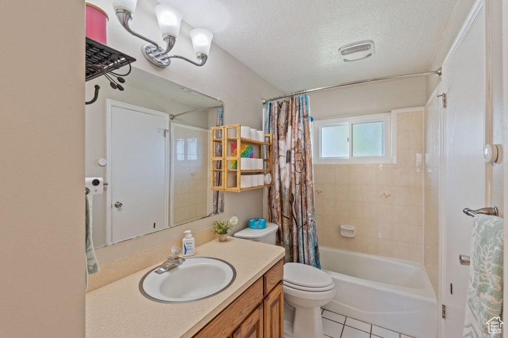 Bathroom with toilet, vanity, shower / bath combo with shower curtain, a textured ceiling, and tile patterned floors