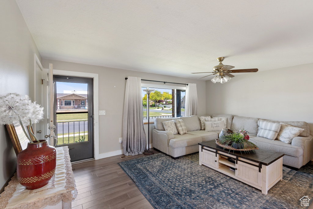 Living area with dark wood-style floors, ceiling fan, and baseboards
