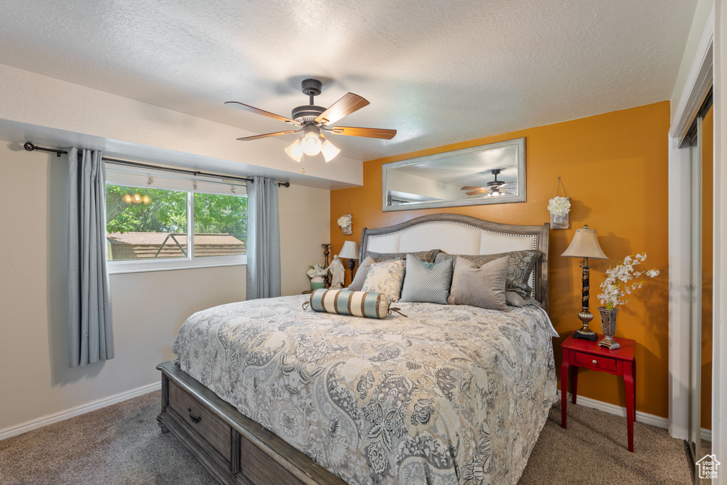 Carpeted bedroom with baseboards, a textured ceiling, and a ceiling fan