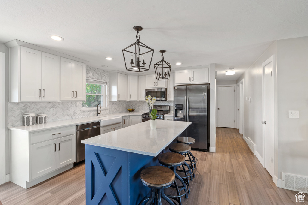 Kitchen featuring appliances with stainless steel finishes, a sink, light wood-type flooring, decorative backsplash, and recessed lighting