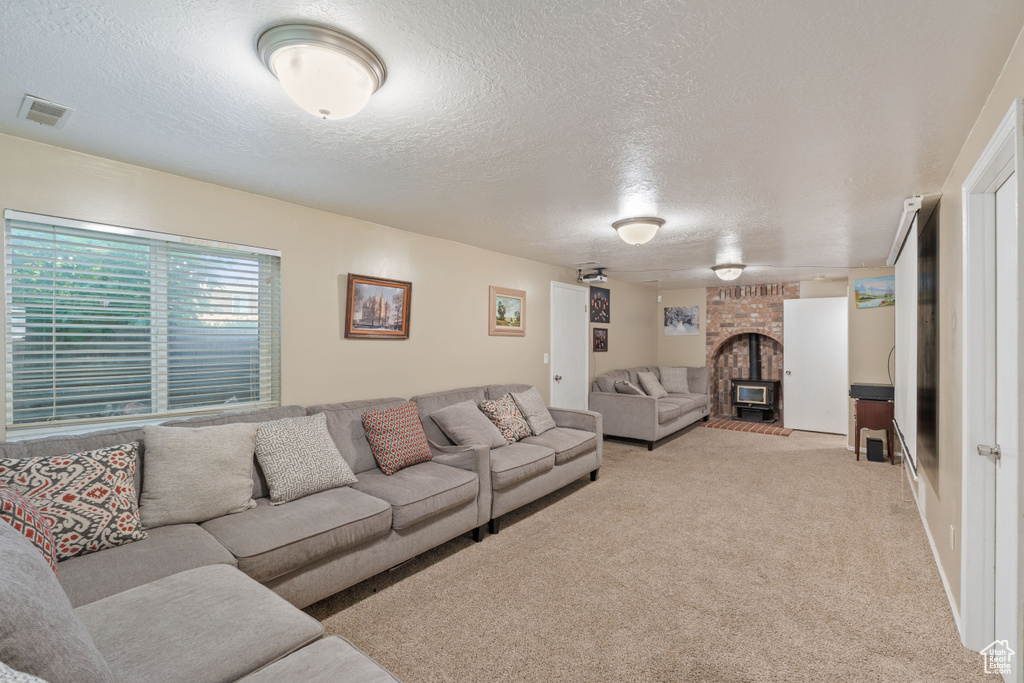 Living area with a textured ceiling, light carpet, and a fireplace