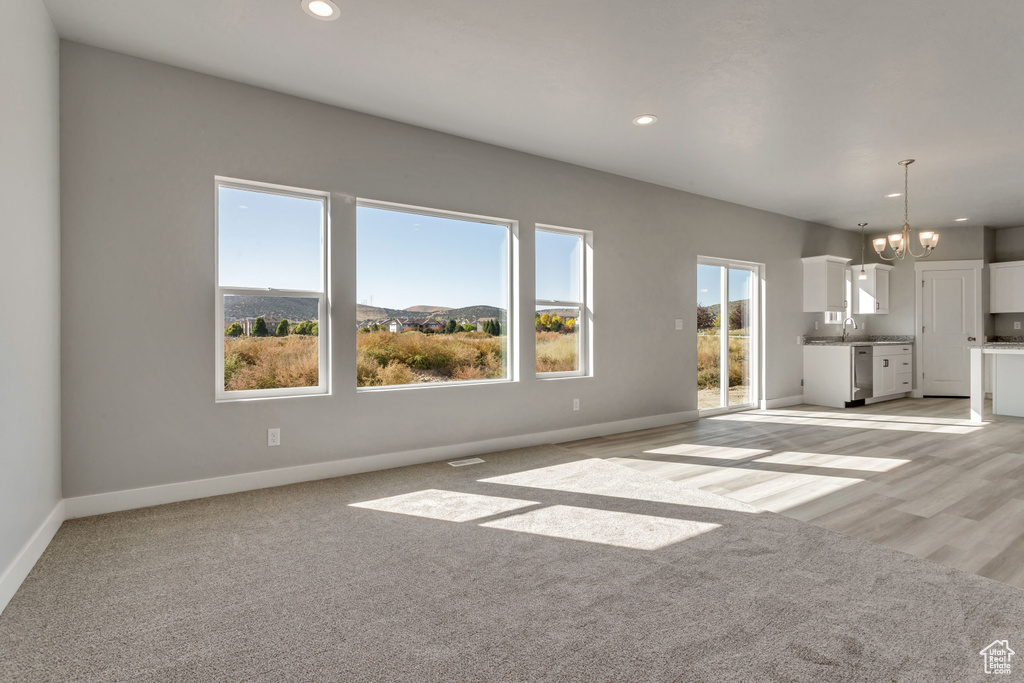 Unfurnished living room with a chandelier, recessed lighting, baseboards, and a sink