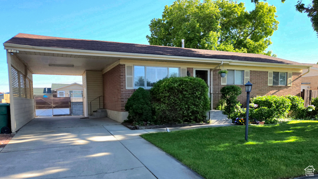 Single story home featuring brick siding, concrete driveway, a front lawn, and an attached carport