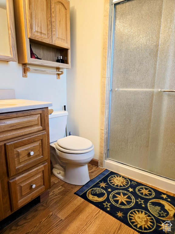 Bathroom featuring vanity, a shower stall, toilet, and wood finished floors