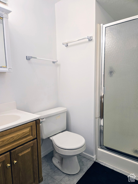 Bathroom featuring vanity, a stall shower, toilet, and baseboards