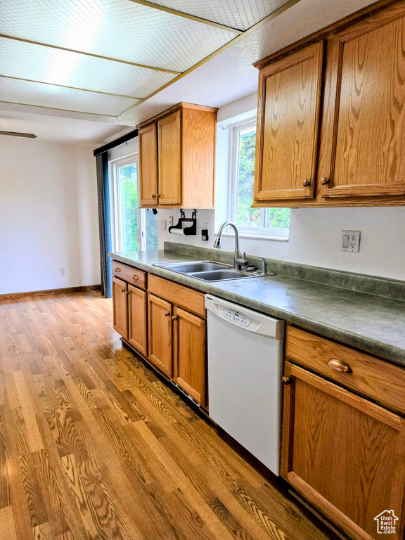 Kitchen featuring dishwasher, a sink, light wood-style flooring, and brown cabinetry