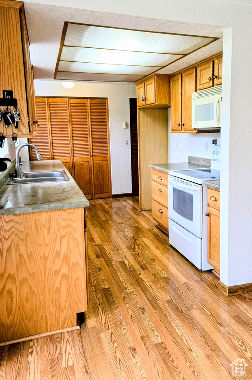 Kitchen with white appliances, a sink, and light wood-style flooring