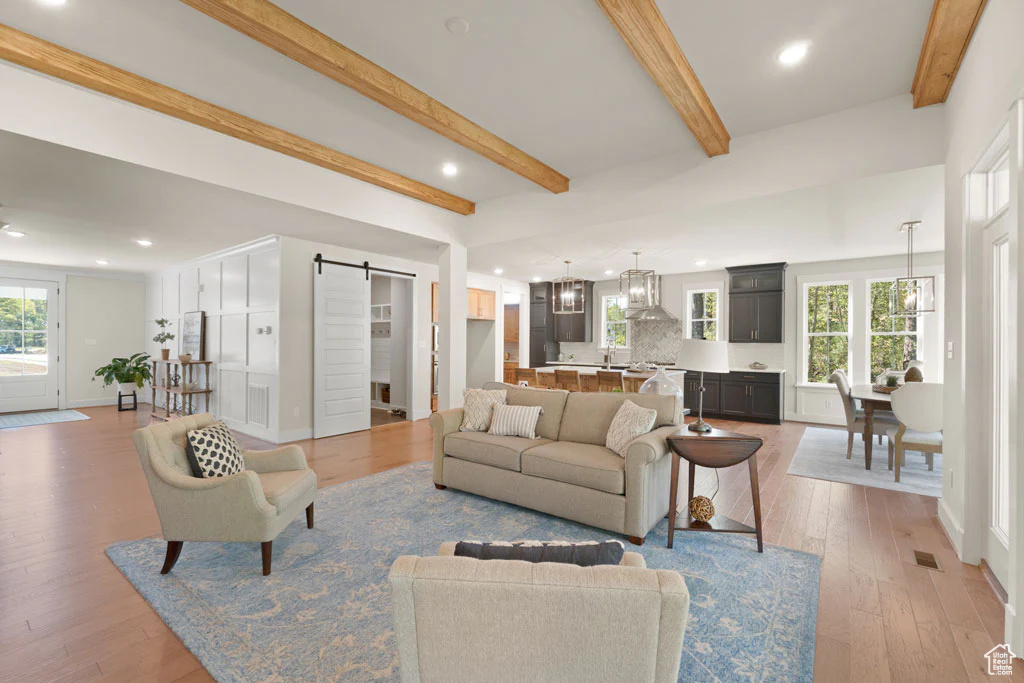 Living area with a barn door, beam ceiling, wood-type flooring, recessed lighting, and baseboards