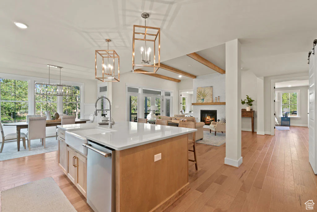 Kitchen with stainless steel dishwasher, a sink, recessed lighting, a fireplace, and an island with sink