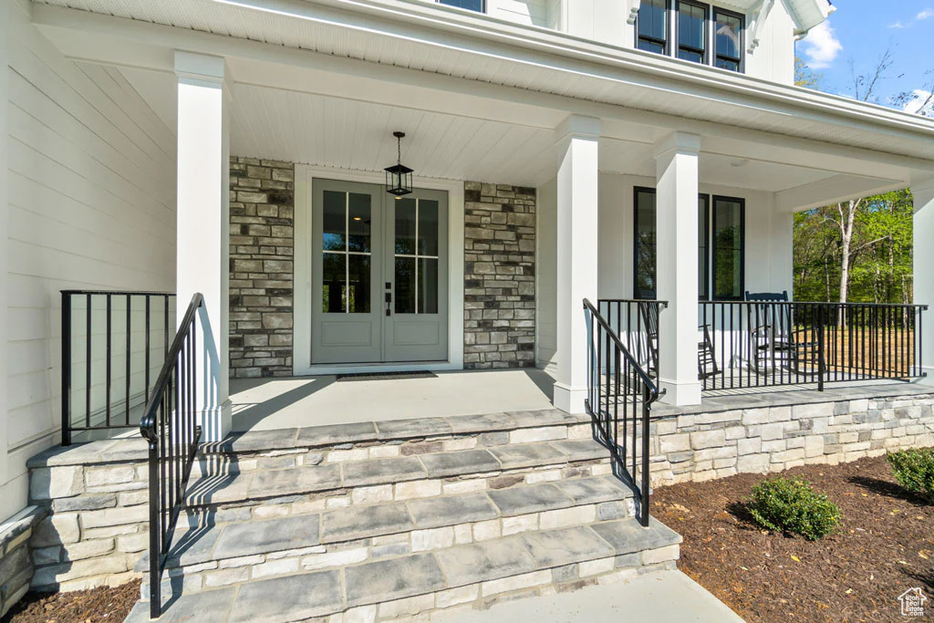 View of exterior entry with a porch and stone siding