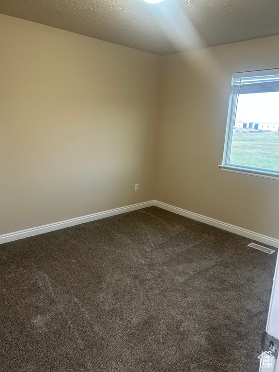 Spare room with dark carpet and baseboards