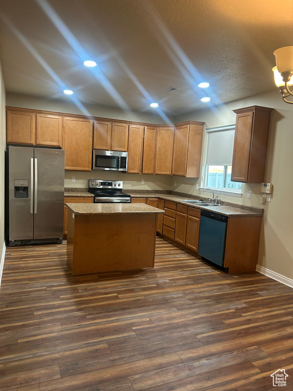 Kitchen with stainless steel appliances, dark wood-style floors, a kitchen island, recessed lighting, and baseboards