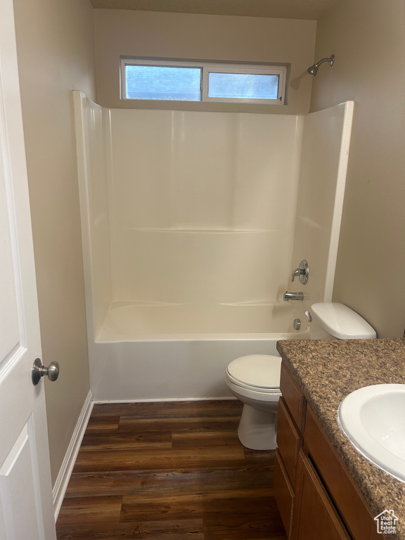 Full bath featuring toilet, vanity, wood finished floors, and shower / tub combination
