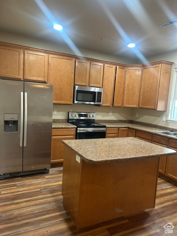 Kitchen with stainless steel appliances, dark wood-style flooring, a center island, recessed lighting, and a sink