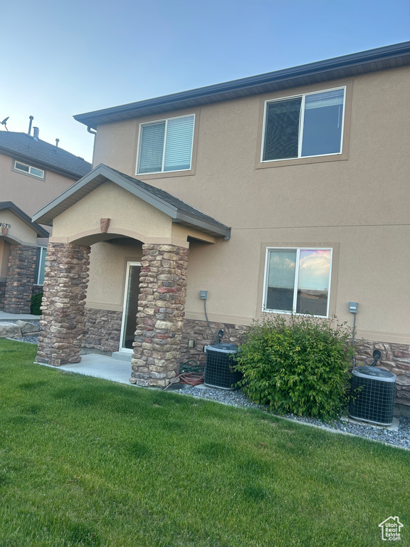 View of front facade featuring stucco siding, central AC, and a front lawn