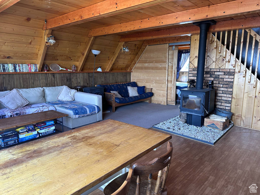 Living area featuring wood walls, wood ceiling with exposed beams, wood finished floors, and a wood stove