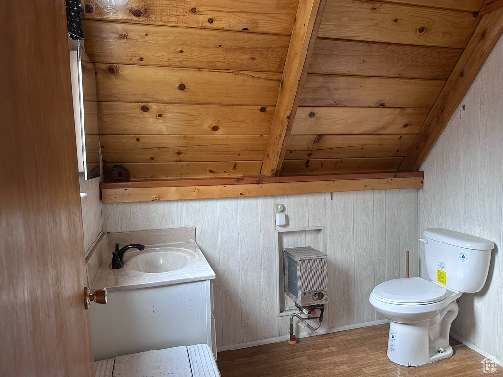 Bathroom featuring wood finished floors, vanity, toilet, wooden ceiling with exposed beams, and heating unit