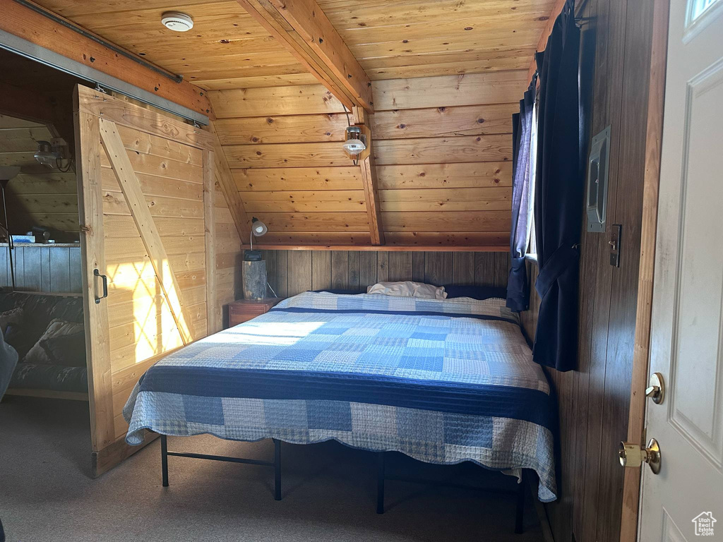 Carpeted bedroom with wood ceiling and wood walls