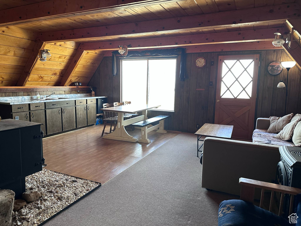 Carpeted living area with wood ceiling, wood walls, a sink, and wood finished floors