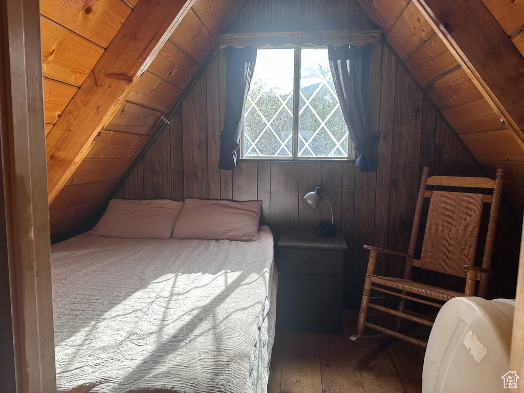 Bedroom featuring wood walls, hardwood / wood-style flooring, vaulted ceiling, and wooden ceiling