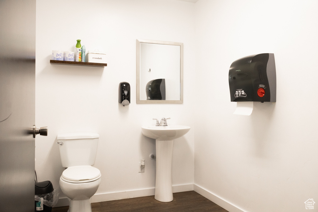 Bathroom with toilet, baseboards, and wood finished floors