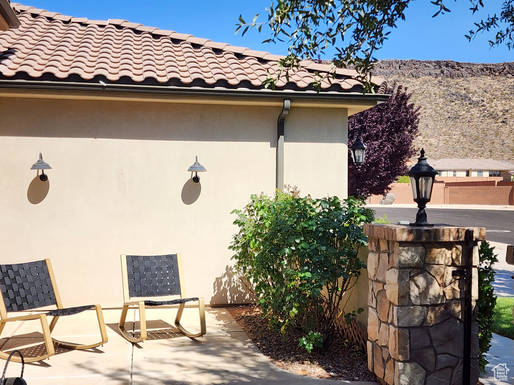 View of home's exterior with stucco siding, a tile roof, a mountain view, and a patio area