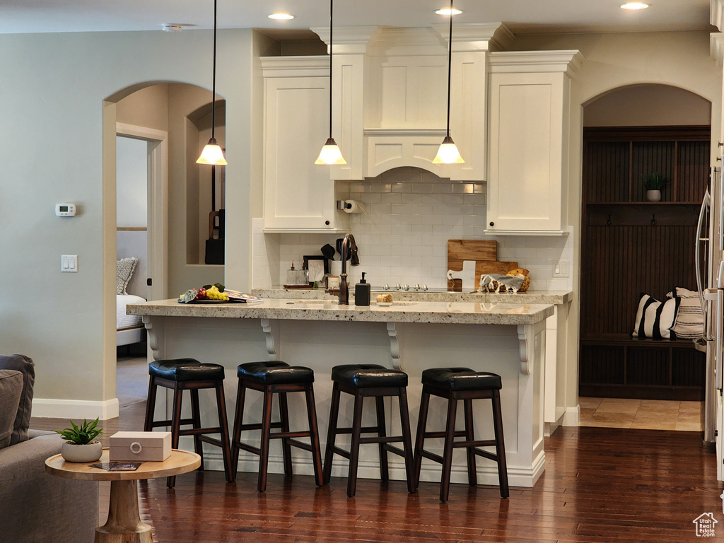 Kitchen with arched walkways, backsplash, white cabinetry, and recessed lighting