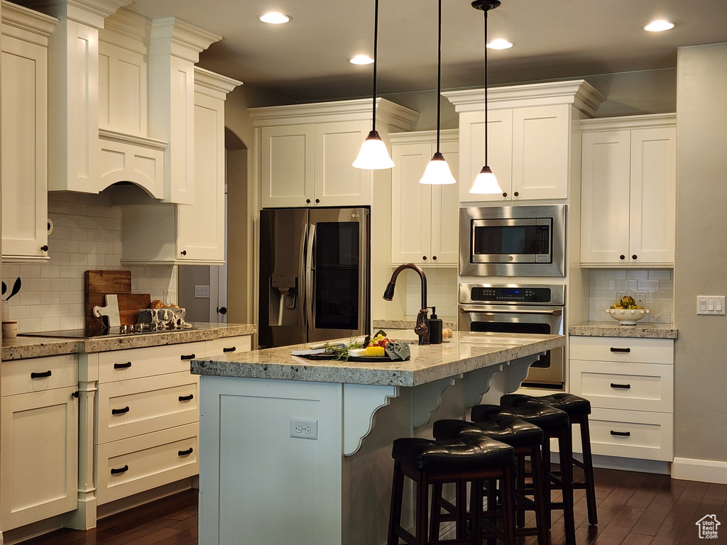 Kitchen with appliances with stainless steel finishes, dark wood finished floors, decorative backsplash, recessed lighting, and white cabinets