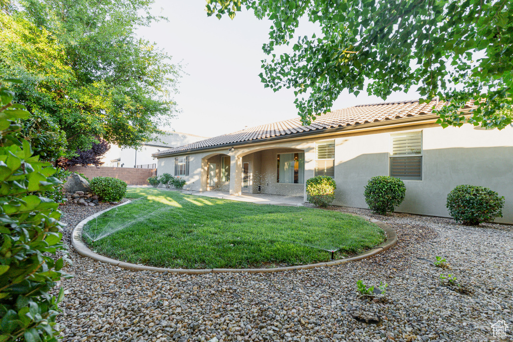 Rear view of house featuring a tile roof, stucco siding, and a patio