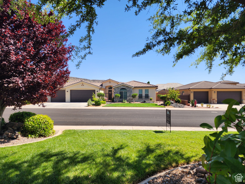 View of front of property with a front lawn, stucco siding, stone siding, and a tiled roof
