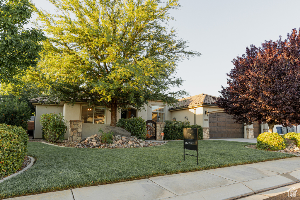 View of front of home featuring stone siding, stucco siding, a front yard, and an attached garage
