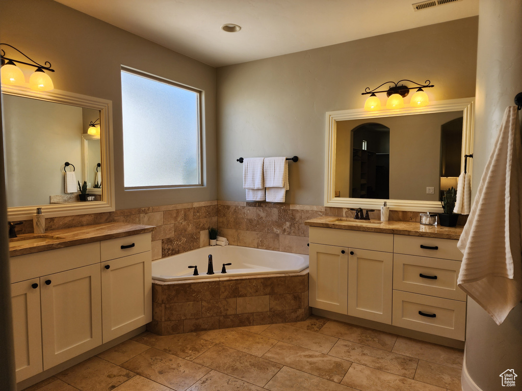 Full bathroom featuring two vanities and a garden tub