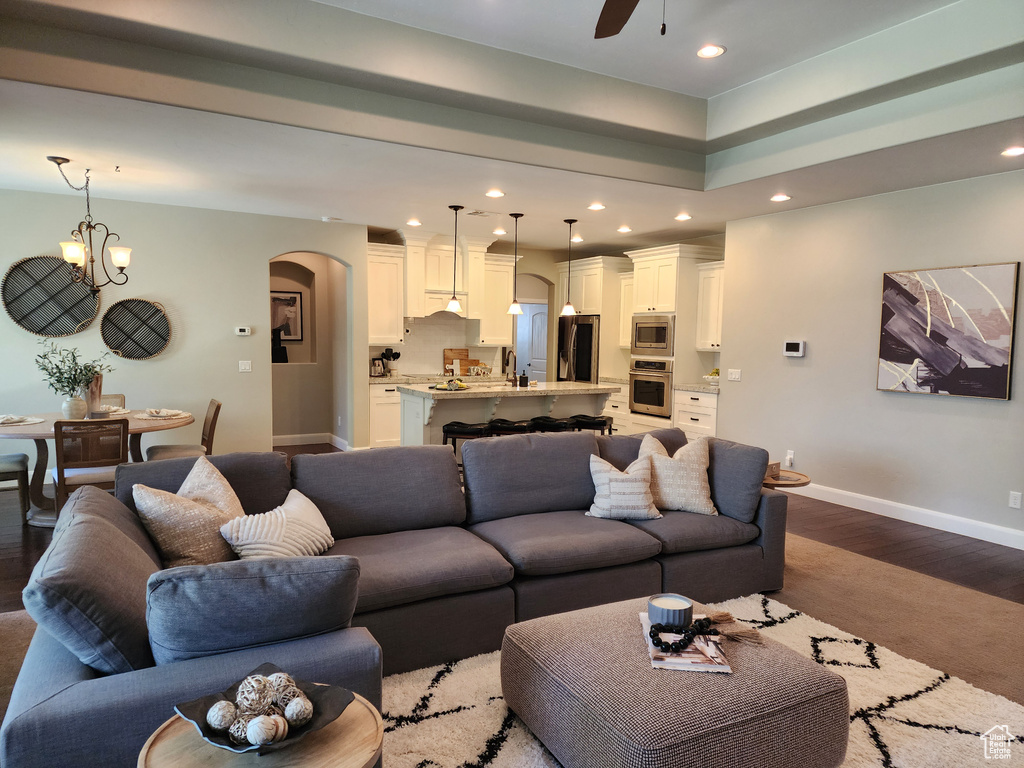 Living area with arched walkways, baseboards, recessed lighting, a ceiling fan, and dark wood-type flooring