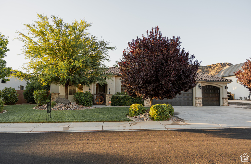 View of property hidden behind natural elements with stone siding, stucco siding, and a tile roof
