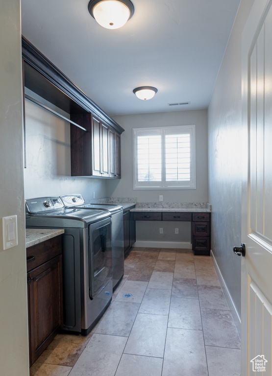 Laundry room featuring cabinet space, independent washer and dryer, baseboards, and light tile patterned floors
