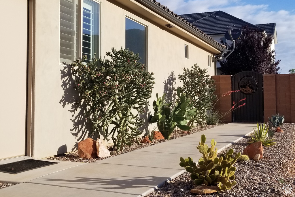 View of side of home with stucco siding and a gate