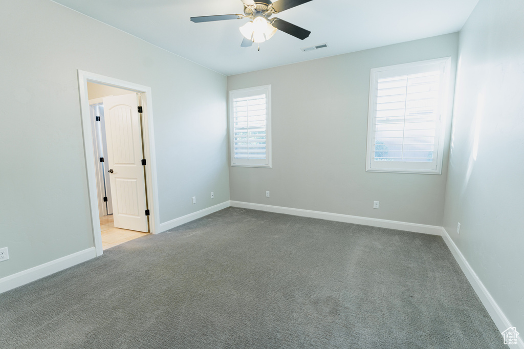 Spare room featuring ceiling fan, carpet, and baseboards