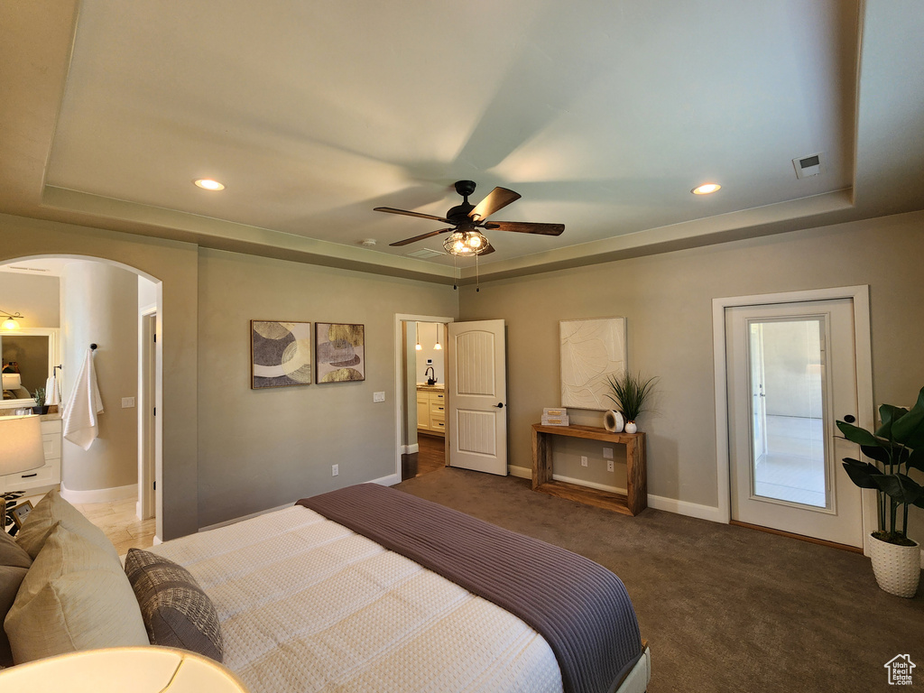 Bedroom with a raised ceiling, arched walkways, baseboards, carpet flooring, and recessed lighting