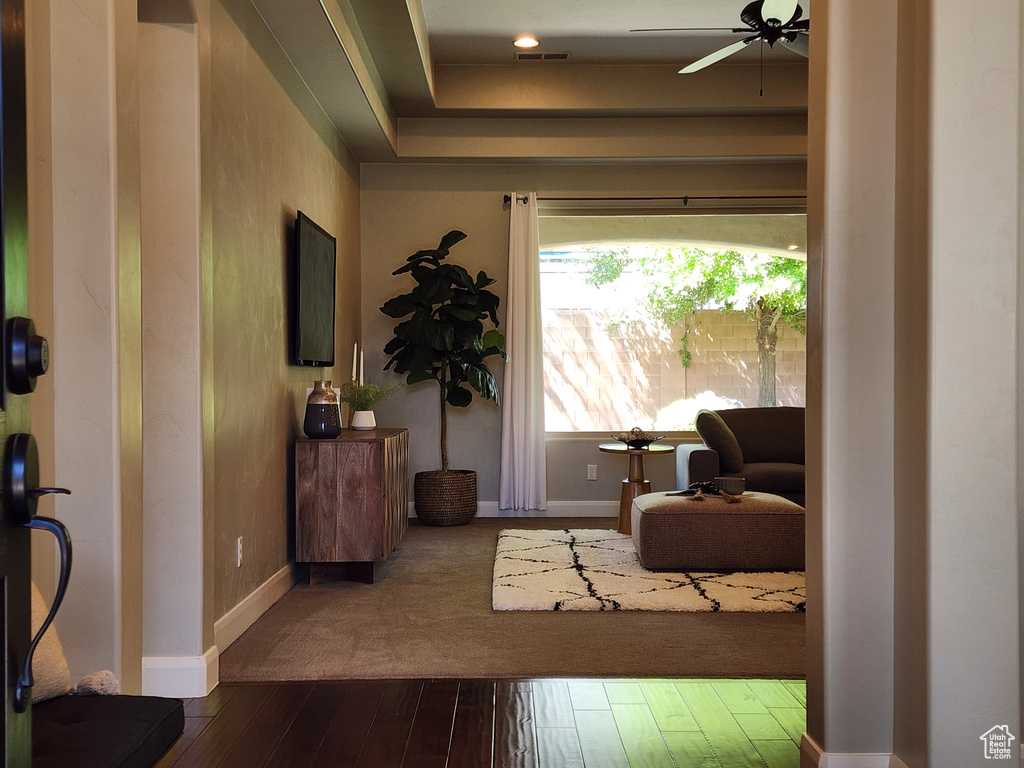 Sitting room with ceiling fan, baseboards, and dark wood-style flooring