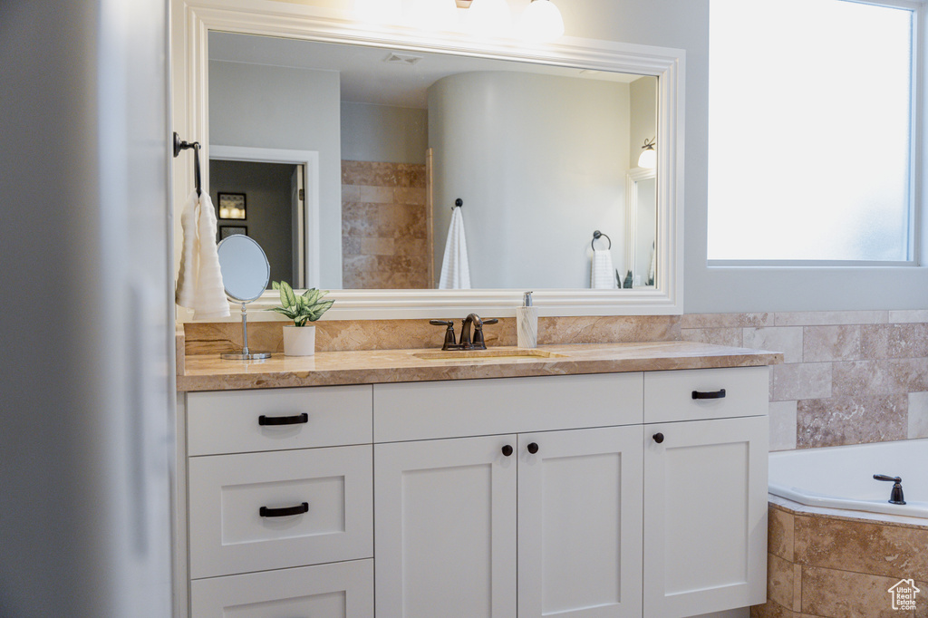 Bathroom with healthy amount of natural light, vanity, and a bath