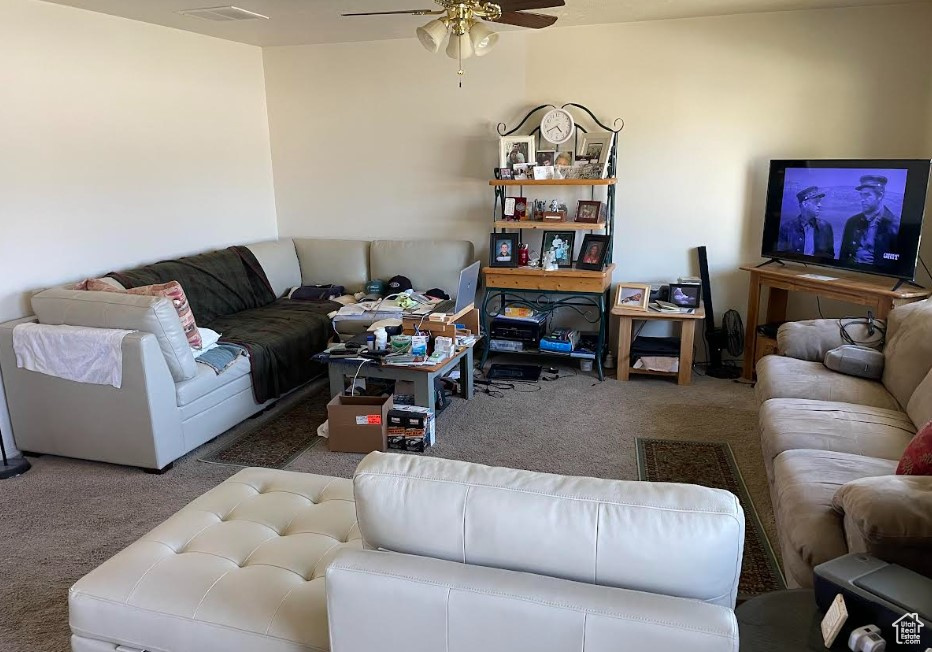 Carpeted living area featuring ceiling fan