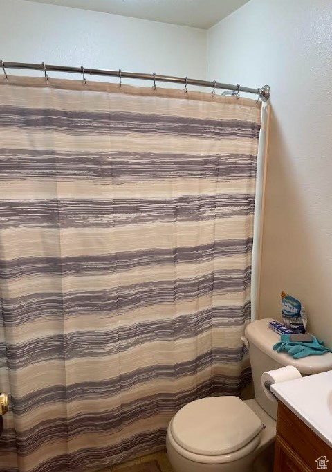 Bathroom with vanity, toilet, and curtained shower