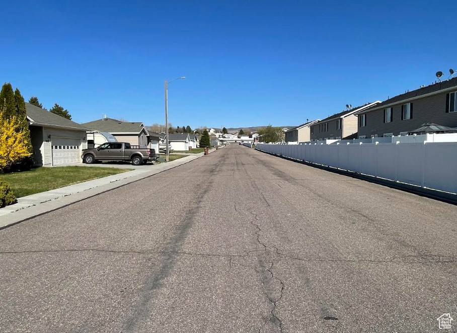 View of asphalt street featuring a residential view and street lighting